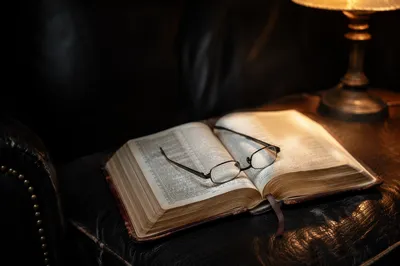 Open Bible with Glasses in Warm Lamplight