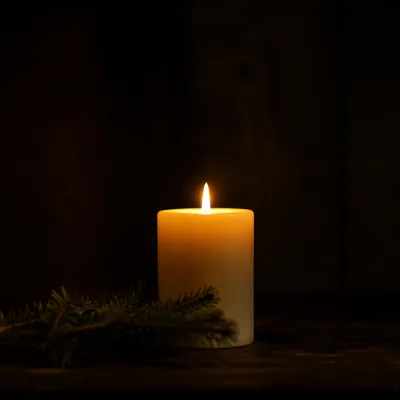 Burning Candle on Dark Evergreen Background
