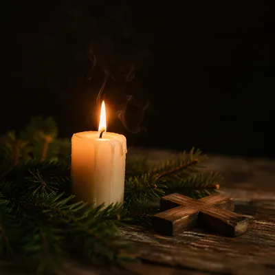 Burning Candle with Evergreen and Wooden Cross