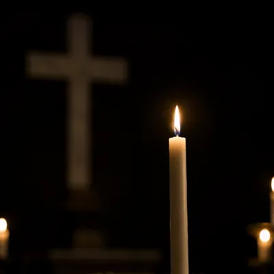Burning Candle with Cross in Darkness