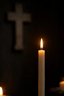 Burning Candle with Cross in Darkness