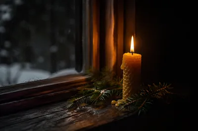 Burning Candle with Evergreen in Winter Darkness