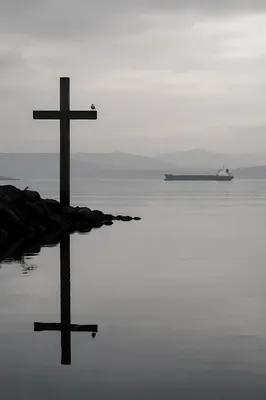 Weathered Cross Reflected in Still Coastal Water