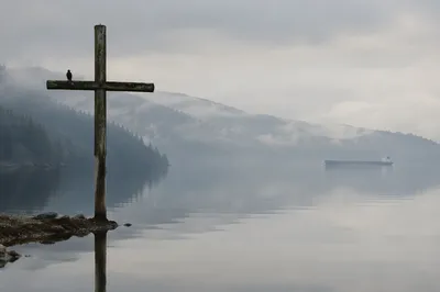 Weathered Cross Reflected in Misty Evergreen Lake