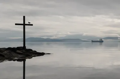 Weathered Cross Reflected in Still Coastal Water