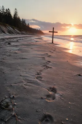 Footprints Leading to Driftwood Cross at Sunrise