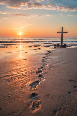 Footprints Leading to Driftwood Cross at Sunrise