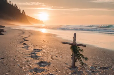 Footprints Toward Sunrise Beside Driftwood Cross