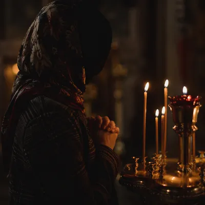 Folded Hands in Candlelit Prayer