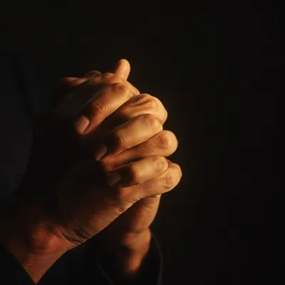 Folded Hands in Warm Prayer Candlelight