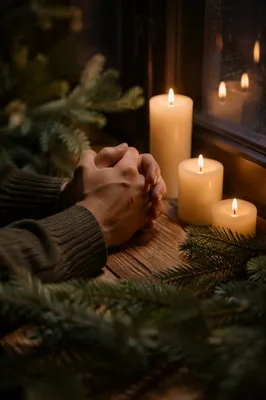 Candlelit Praying Hands with Evergreen Sprigs