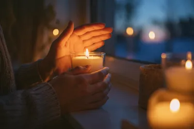 Folded Prayer Hands Beside Candlelight