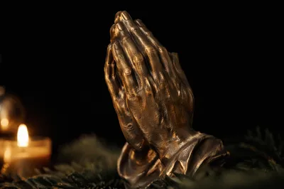 Candlelit Bronze Praying Hands with Evergreen