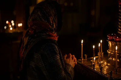 Folded Hands in Candlelit Prayer