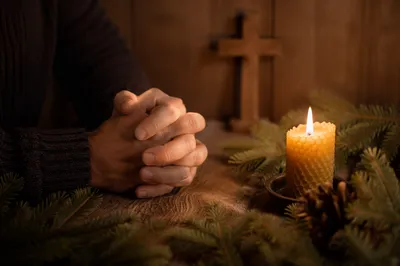 Candlelit Praying Hands with Evergreen Sprigs