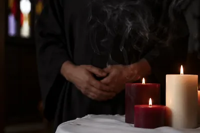 Folded Hands in Candlelit Prayer