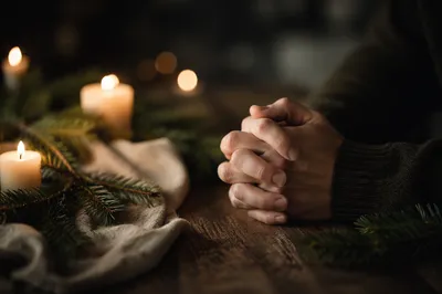 Folded Prayer Hands in Evergreen Candlelight