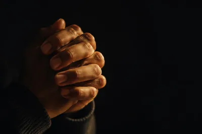 Folded Hands in Warm Candlelight Prayer