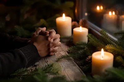 Folded Hands in Candlelit Evergreen Prayer