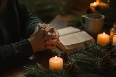 Candlelit Prayer Hands with Evergreen Devotion