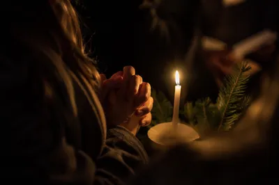 Candlelit Prayer Hands with Evergreen Sprigs