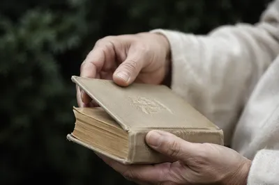 Reverent Hands Holding Worn Bible Outdoors