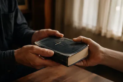 Hands Gently Passing a Worn Bible
