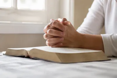 Praying Hands on Open Book in Soft Light