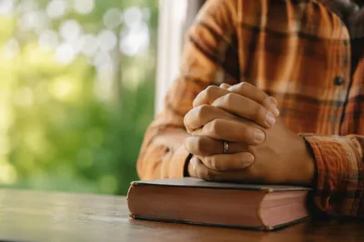 Praying Hands on Worn Book in Soft Light