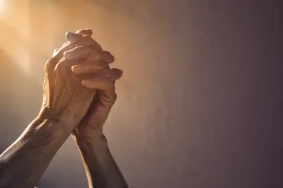 Older Hands Praying in Warm Soft Light