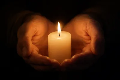 Praying Hands Holding Candle in Soft Light