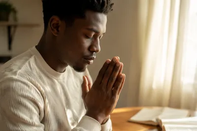 Young Man Praying by Sunlit Window
