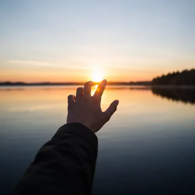 Hand Reaching Toward Sunrise Light
