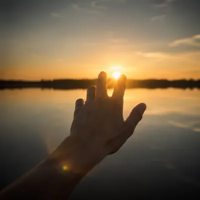 Hand Reaching Toward Golden Horizon Light