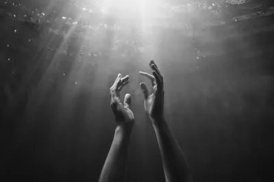 Hands Reaching Toward Hopeful Light