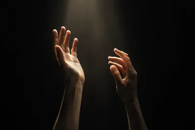 Hands Reaching Toward Soft Light
