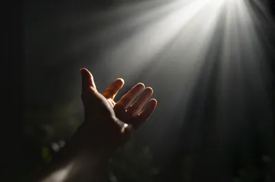 Hand Reaching Toward Hopeful Divine Light
