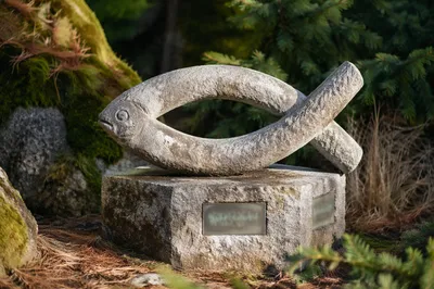 Weathered Ichthys Stone Sculpture in Evergreen Garden