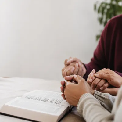 Hands Clasped Beside Open Devotional Book