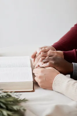 Clasped Hands Beside Open Devotional Book