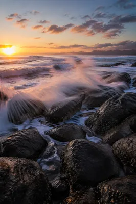 Sunrise Waves Crashing Over Rocky Shoreline