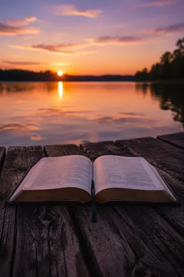 Open Bible by Calm Lake at Sunset