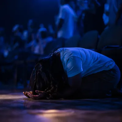 Kneeling in Quiet Prayer Under Blue Light