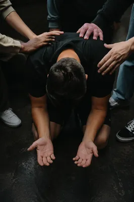 Person Kneeling in Supportive Prayer Circle