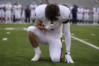 Athlete Kneeling in Prayer on Turf