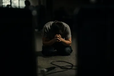 Person Kneeling in Dim Prayer Room
