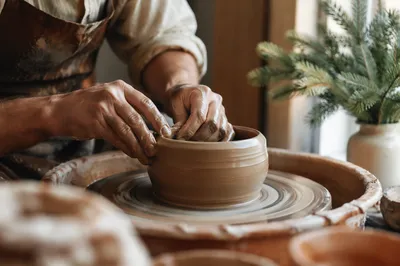Potter Hands Shaping Clay with Evergreen Light