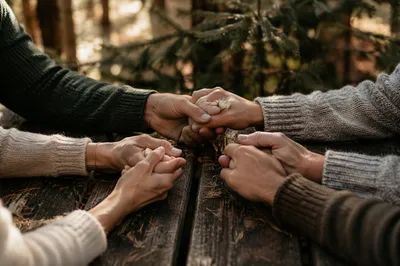 Prayer Group Hands Joined Beneath Evergreens