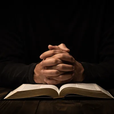 Praying Hands Over Open Bible