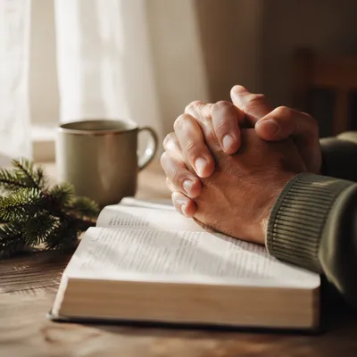 Praying Hands Above Open Bible